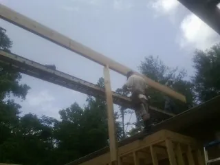 Carpenter setting a ridge beam over a new addition frame — Ice Dam Removal by Roofing Brothers in Newalla