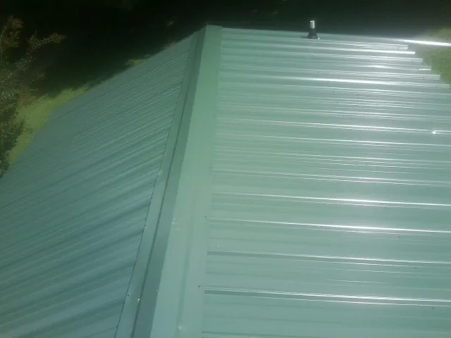 New green metal panels meeting at the ridge of a roof — Flat Roof Repair work by our crew in Newalla