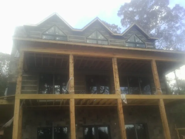 Dormers and porch framing on a large log home under construction — Roof Coating work by our crew in Newalla