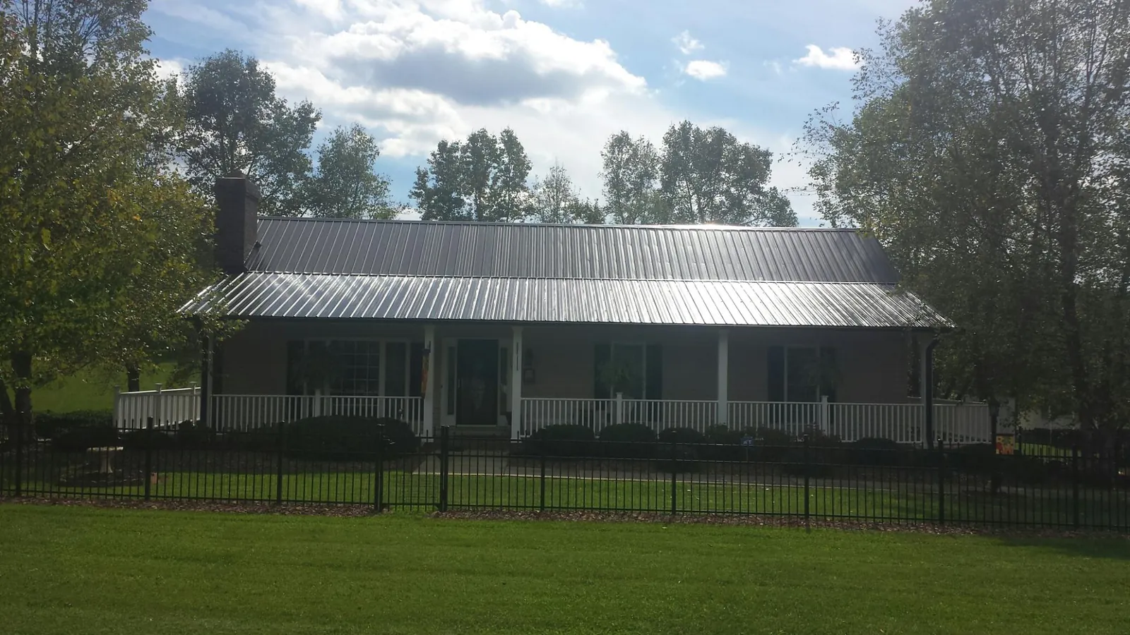Gray metal roof on a brick ranch with a full width front porch — Gutter Guard Installation work by our crew in Newalla