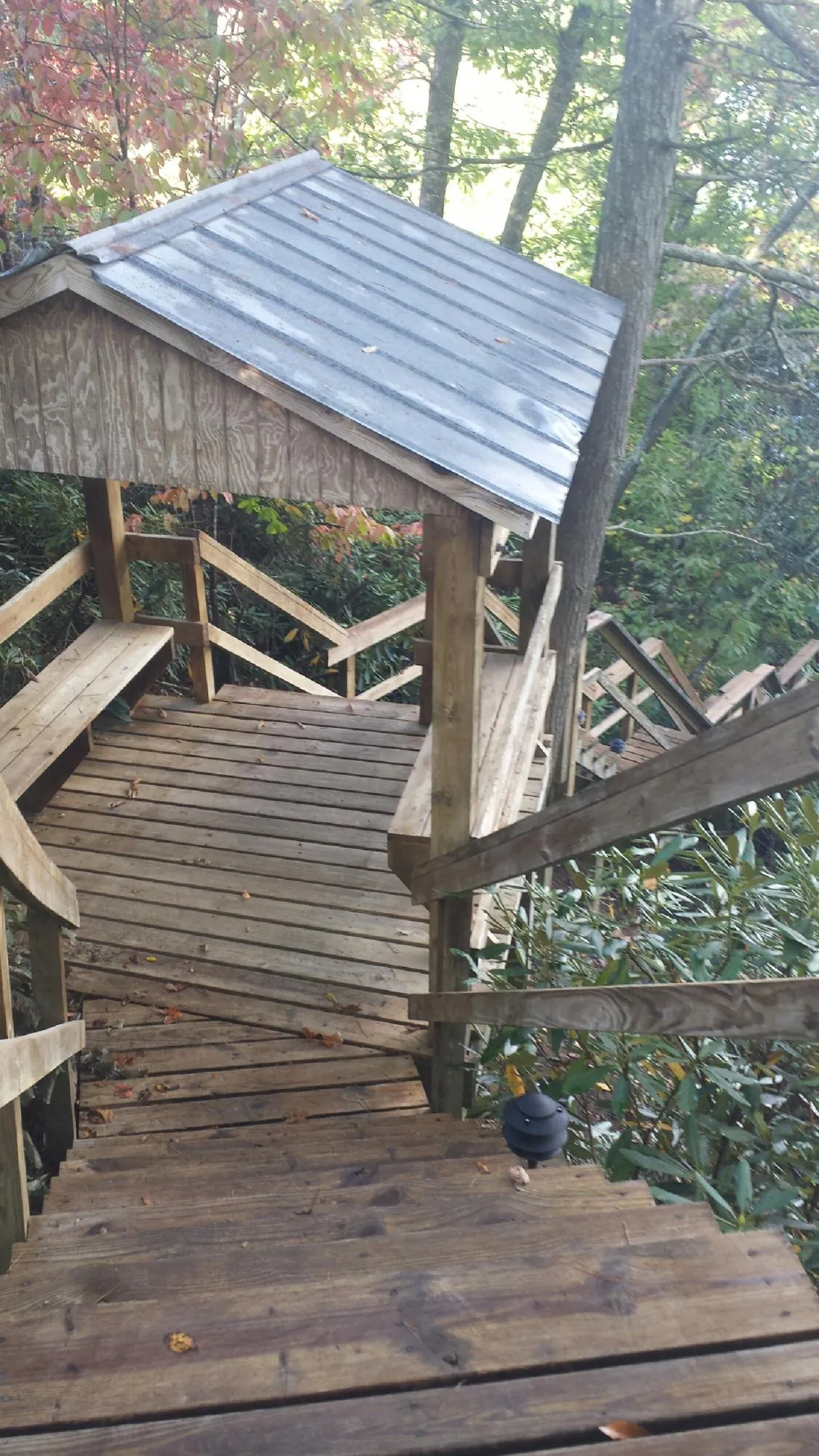 Metal roofed shelter over wooden steps on a wooded walkway — Skylight Repair & Installation work by our crew in Newalla