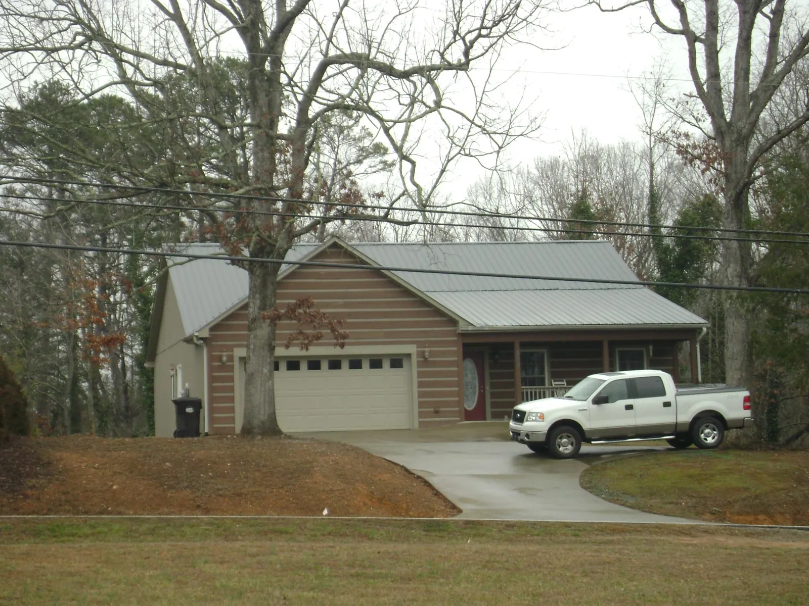 Gray metal roof on a log sided house with an attached two car garage in Newalla